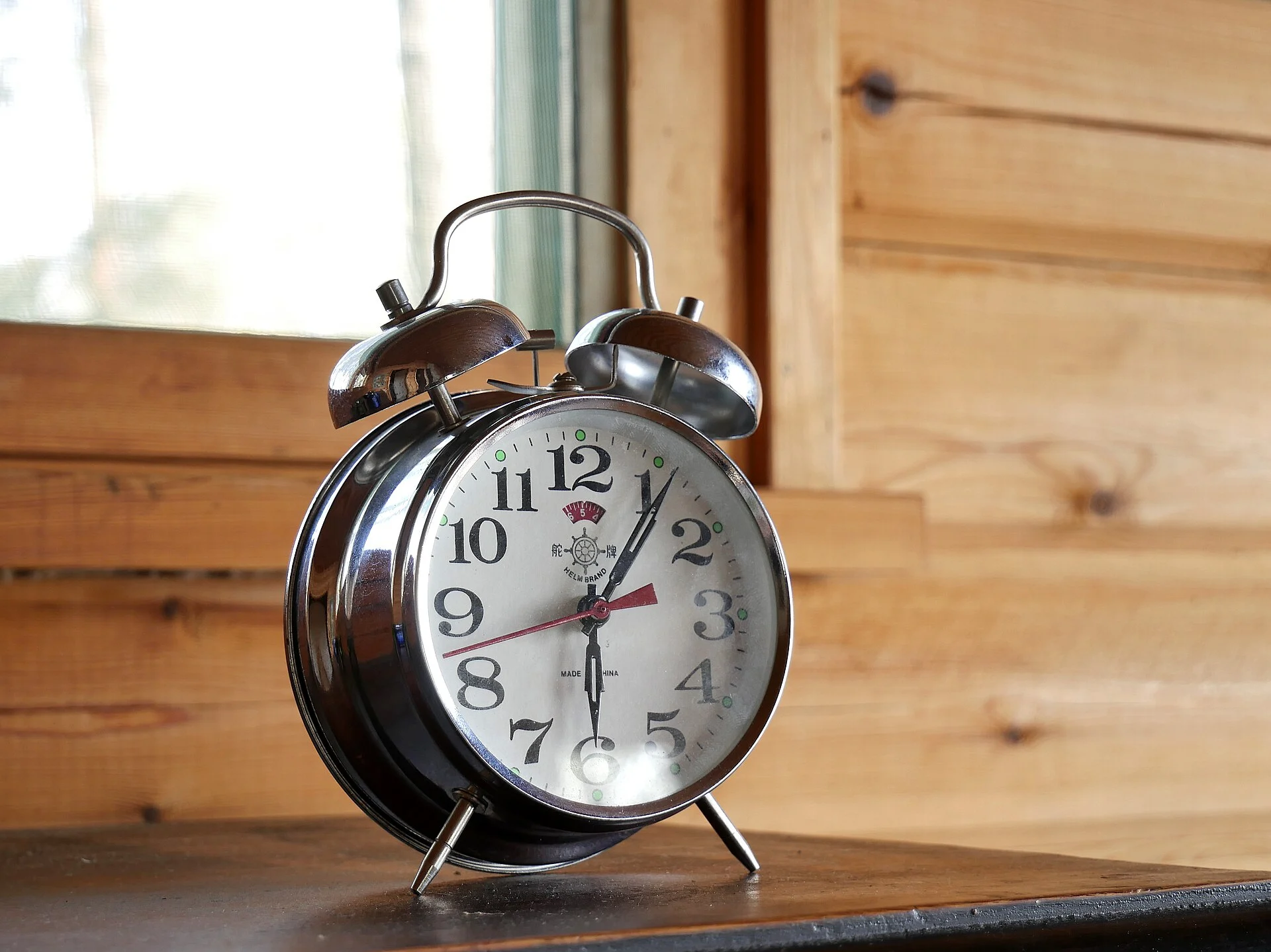 A classic mechanical wind-up alarm clock on a wooden surface